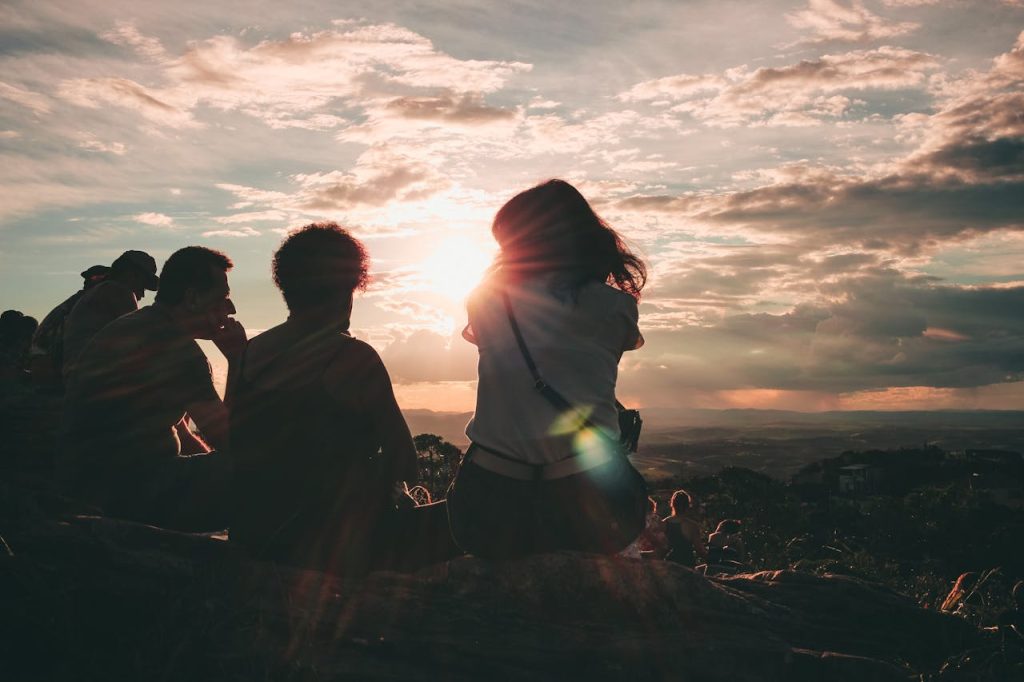 A group of young people sitting down over looking a view from up high against a cloudy sky