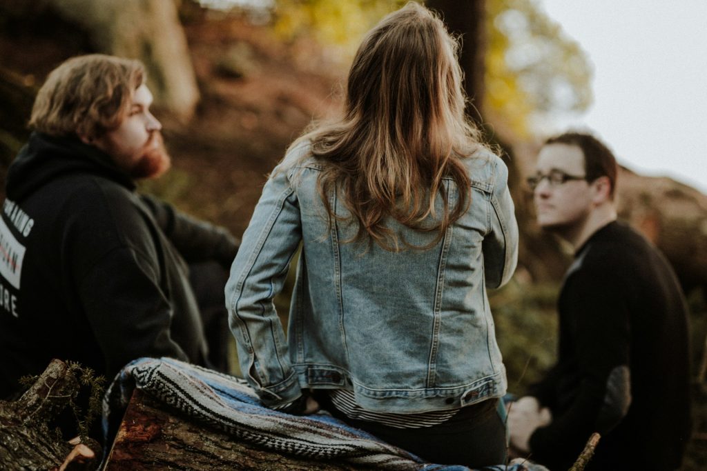 two men and a woman sitting outside having a serious conversation